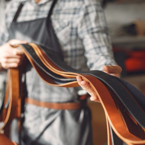 Man working with leather. Professional makes a belts.